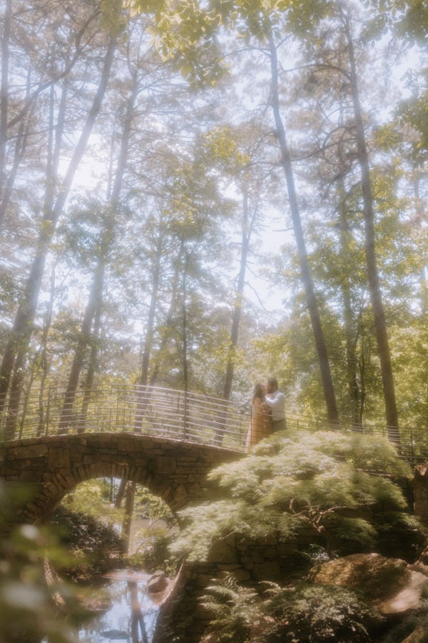 A dreamy photo of a couple embracing for a kiss on the moon bridge at Garvan Woodland Gardens during their Arkansas elopement.