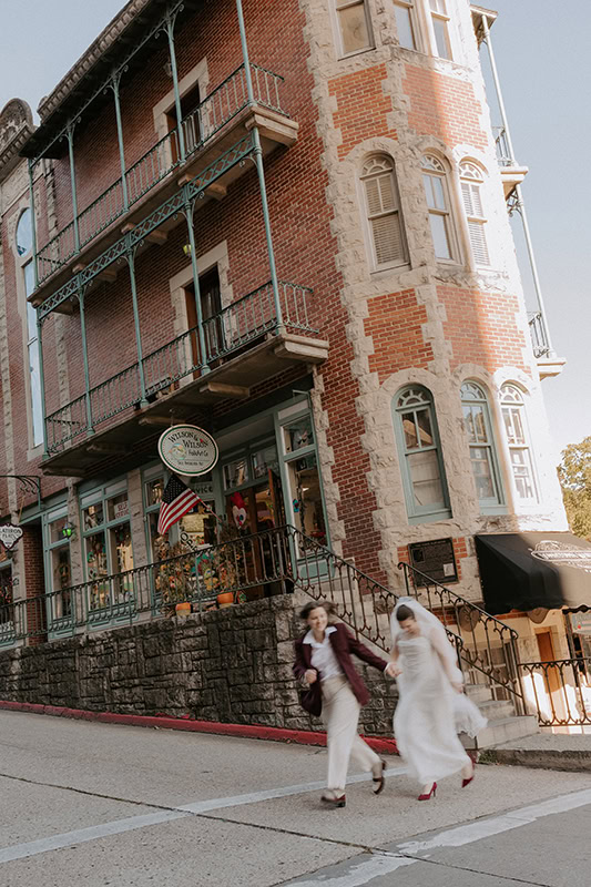 Two brides run across the street in downtown Eureka Springs during their Arkansas elopement.