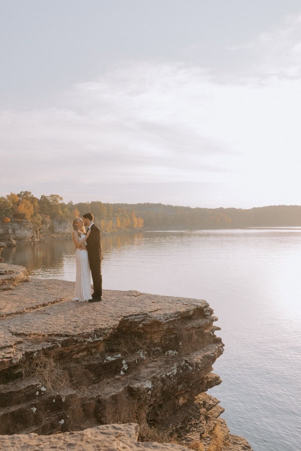 A bride and groom lean in for a kiss on a bluff overlooking Greers Ferry Lake in Heber Springs, Arkansas during their elopement.