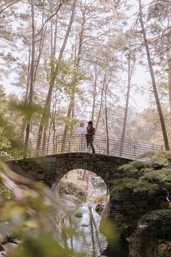 A couple stands next to each other on the moon bridge at Garvan Woodland Gardens taking elopement photos during their Hot Springs, Arkansas elopement.