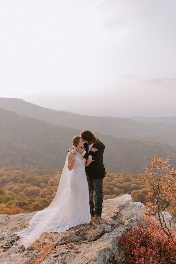 A bride and groom embrace on a mountaintop for elopement photos at Mt. Magazine State Park in Arkansas.