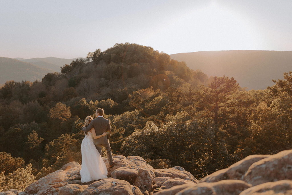 A couple stands on a cliffside overlooking Sam's Throne after they elope in Arknasas.