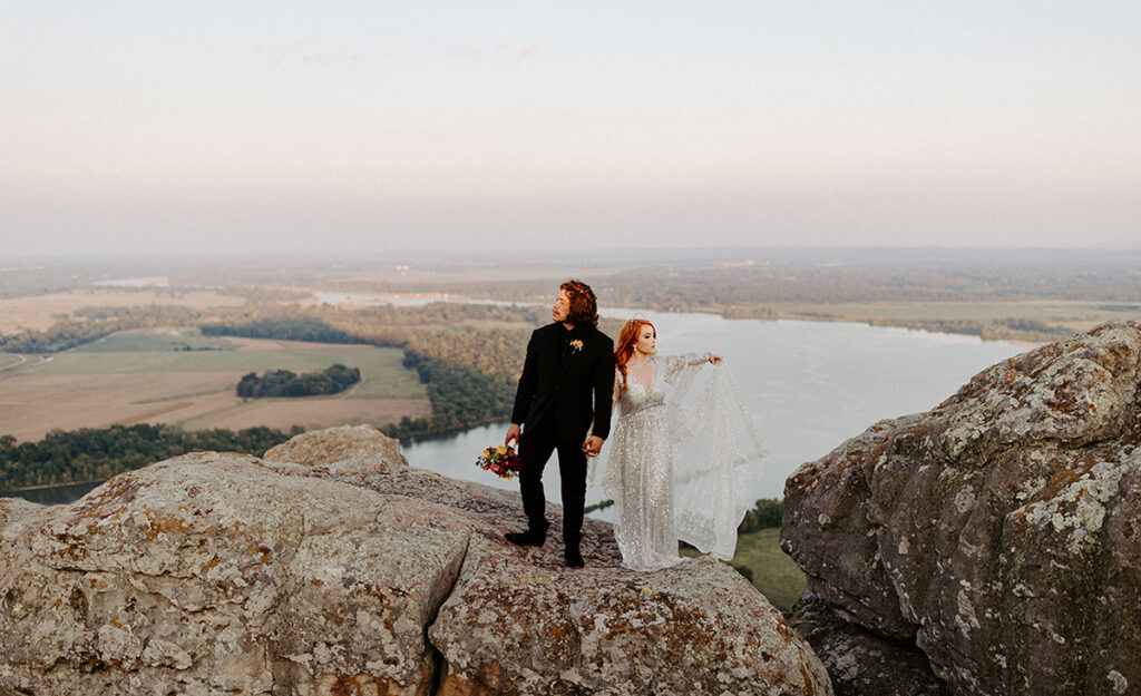 A bride and groom stand atop Stouts Point at Petit Jean State Park to pose for a photo in their wedding attire during their Arkansas elopement.