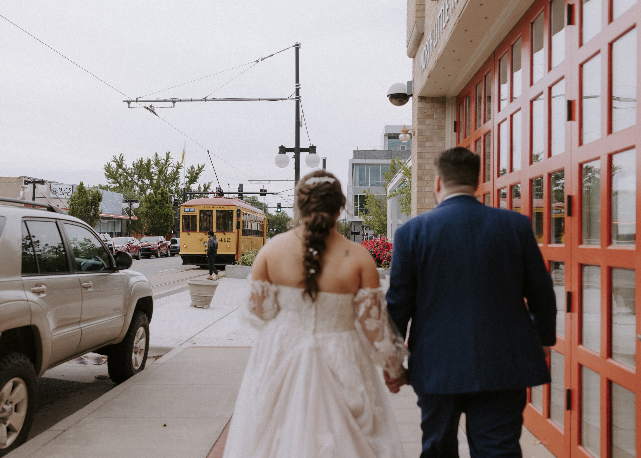 A bride and groom in their wedding attire walk down the street of Argenta District after their ceremony at the Baker in North Little Rock, Arkansas.