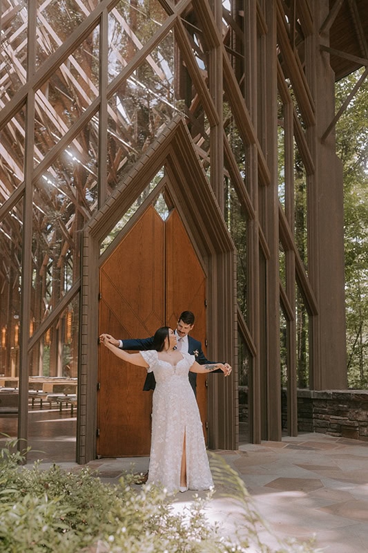 A couple stands in front of the door of Anthony Chapel embracing each other during their photos.