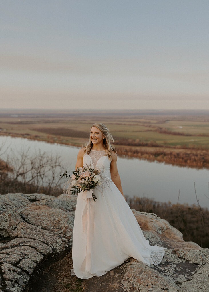 A bride laughs while posing for a photo at Stouts Point during her Arkansas elopement at Petit Jean State Park.