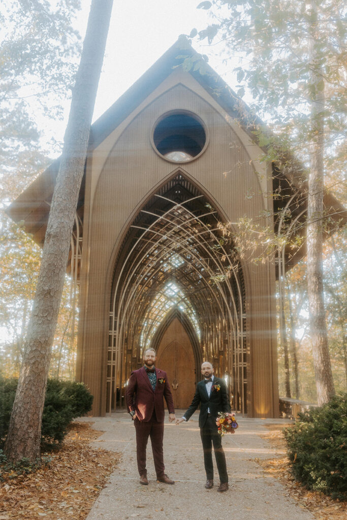 Two grooms stand outside of the Arkansas wedding venue, Cooper Chapel, a popular glass chapel venue in Bella Vista, Arkansas.