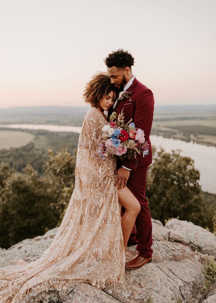 a bride and groom in wedding attire embrace on top of Petit Jean State Park during their Arkansas elopement.