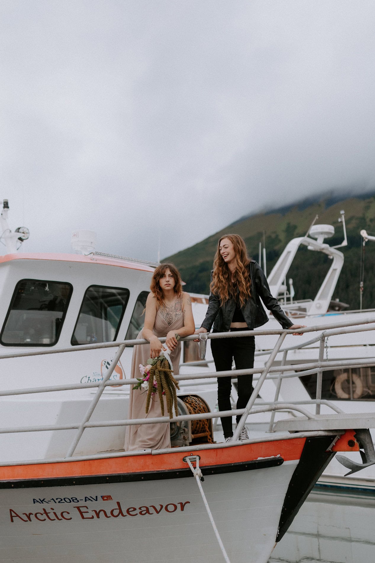 A couple poses on their boat at the Seward boat harbor during their Kenai Fjords adventure elopement.