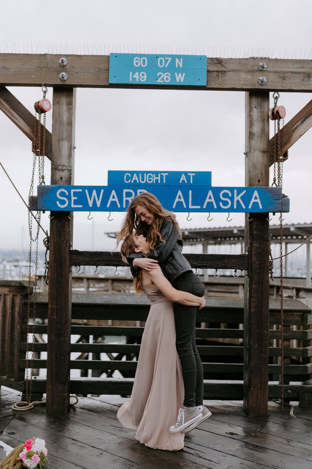 A bride picks up her spouse for a fun photo at the Seward boat harbor in Alaska.