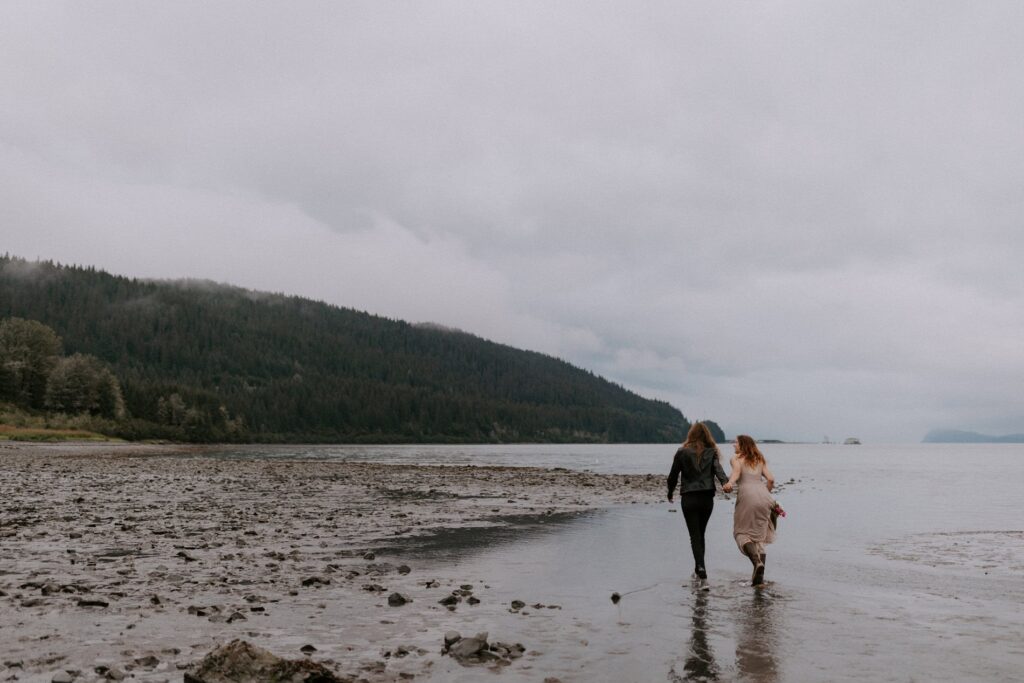 A couple runs along a Seward beach at one of the best places to elope in Alaska.