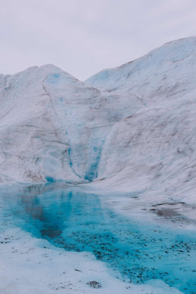 A glacier-waterfall pooling into a vibrant blue melted area of Mendenhall Glacier in Juneau.