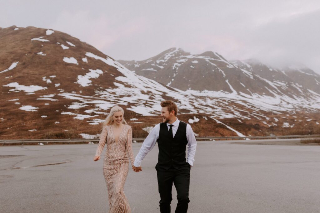 A couple runs down an empty road during their Spring elopement at Hatcher Pass, Alaska.