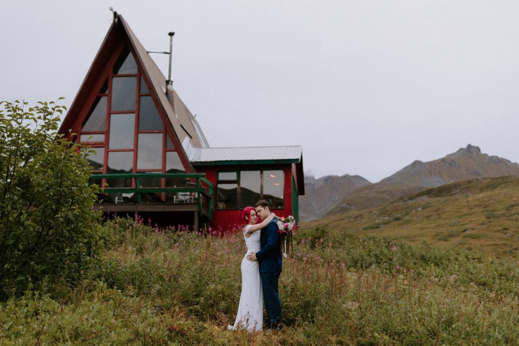An eloping couple hugs in front of the Hatcher Pass Lodge.
