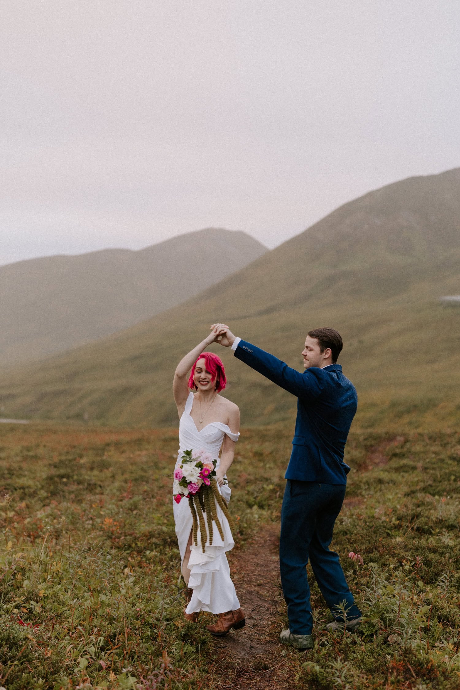 A groom spins his bride in the rain during their moody Hatcher Pass elopement in Alaska