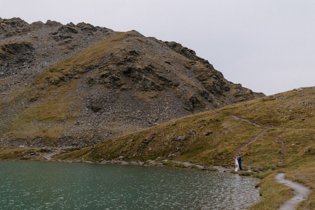 A couple stands next to Summit Lake during their Hatcher Pass elopement in Alaska.