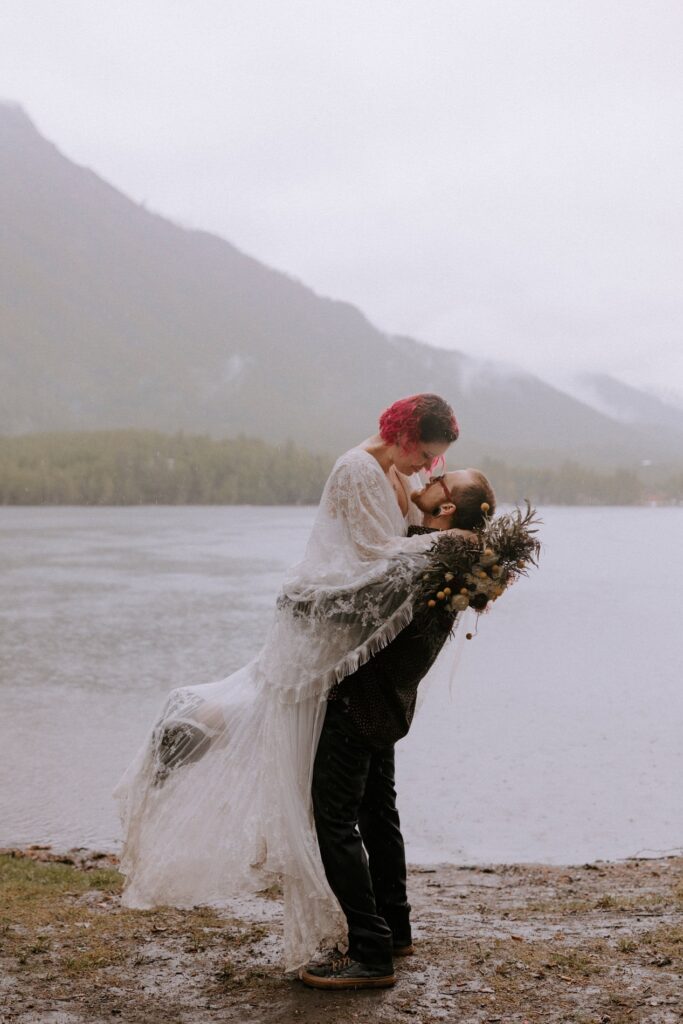 misty outdoor elopement in Alaska by a lake surrounded by mountains.