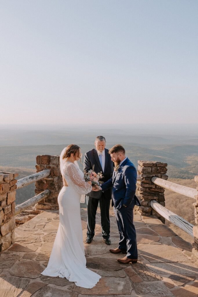 A couple holds hands during their elopement ceremony at Cameron Bluff on Mount Magazine in Arkansas.