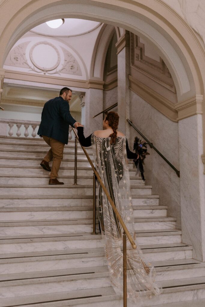 A groom leads his bride upstairs at the Pulaski County Courthouse in Little Rock, Arkansas during their elopement.