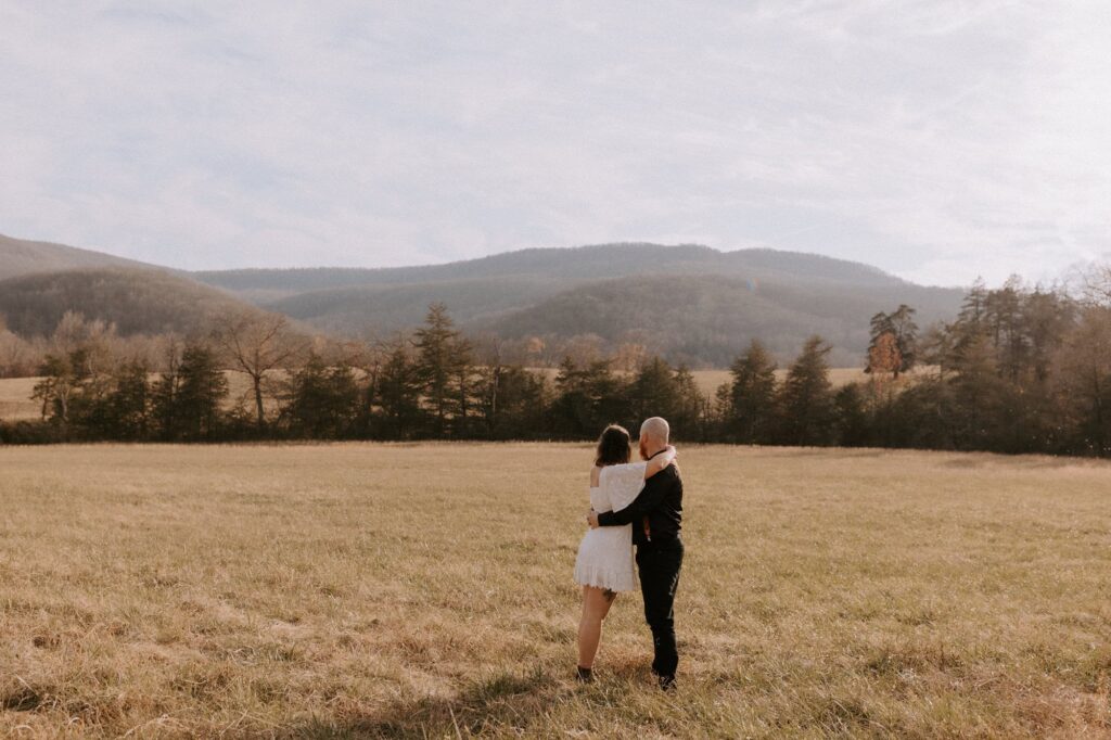 A couple embraces and looks at the hills surrounding Ponca, Arkansas during their Lost Valley elopement.