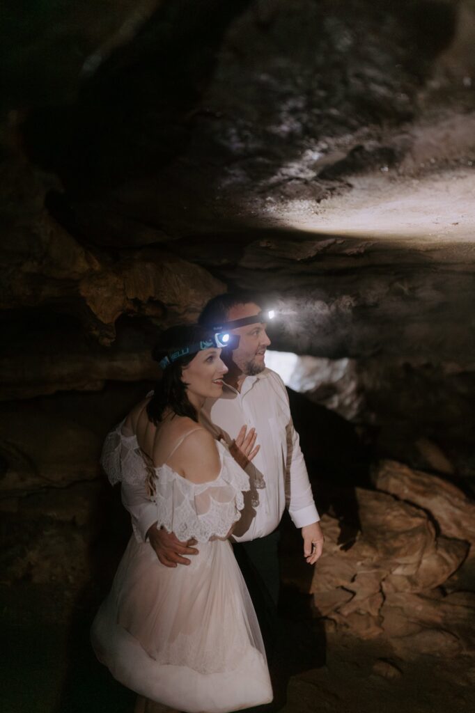 A couple eloping at Lost Valley in Ponca, Arkansas explore Eden Falls Cave with headlamps.