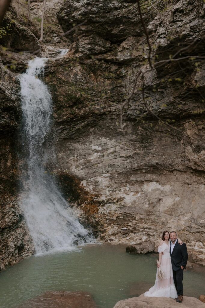 An Arkansas elopement couple poses for a photo below Eden Falls at Lost Valley Trail.