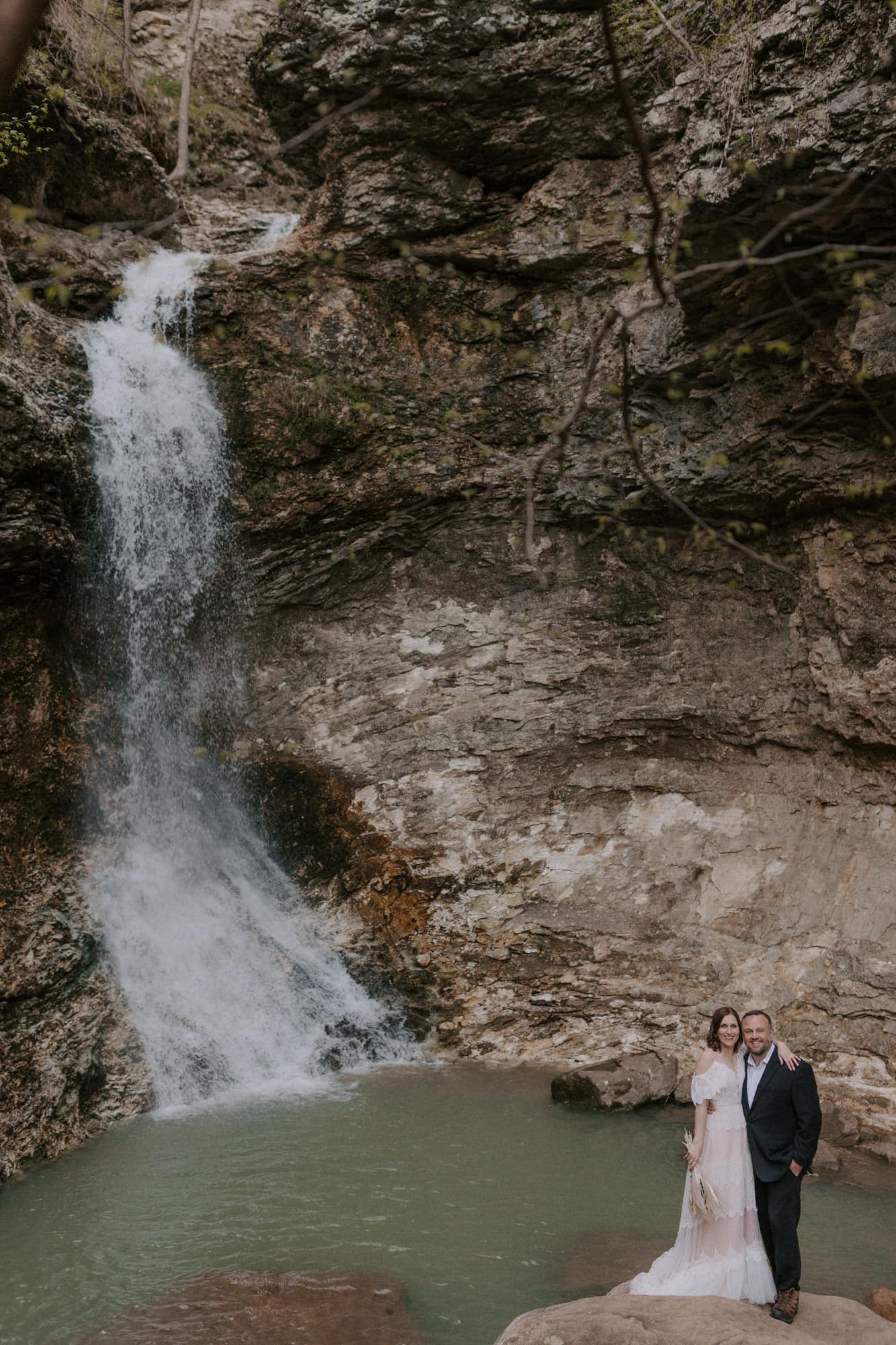 a bride and groom pose for a photo beside Eden Falls during their vow renewal in the Buffalo National River area of Arkansas.