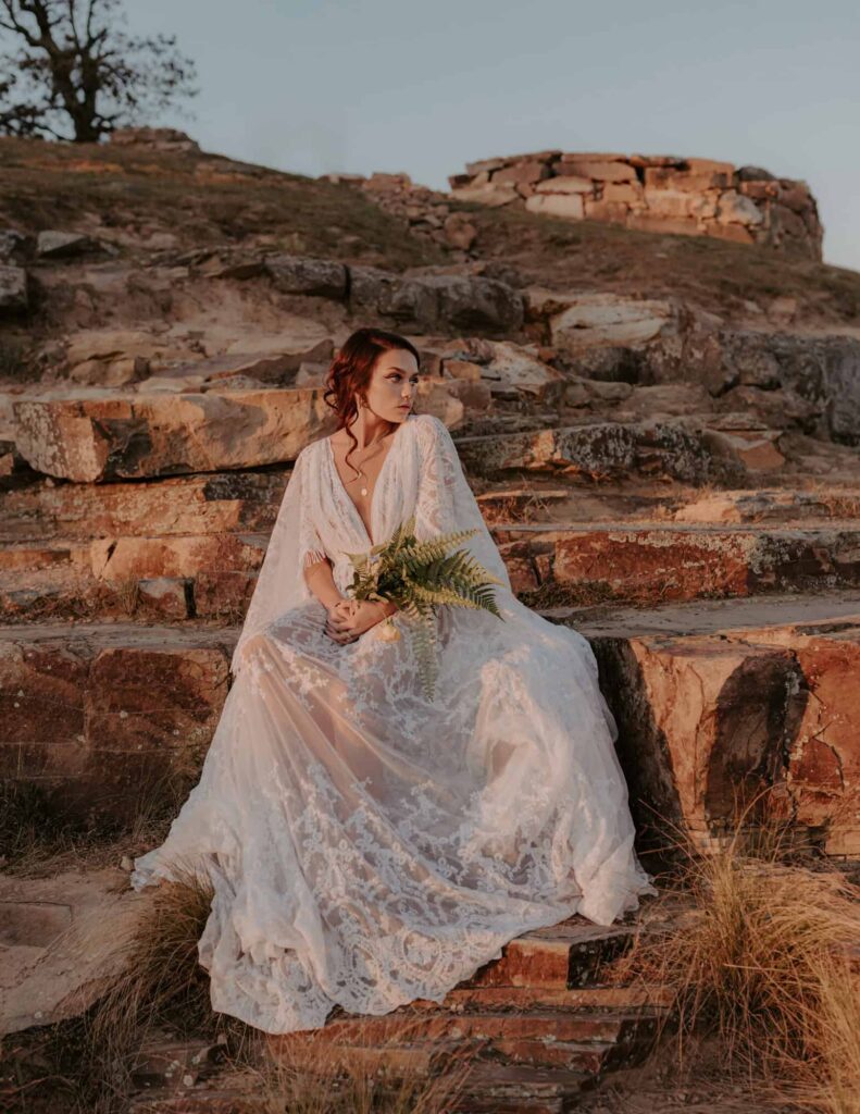A bride poses for a photo while sitting on a rocky ledge at Mt. Nebo State Park.