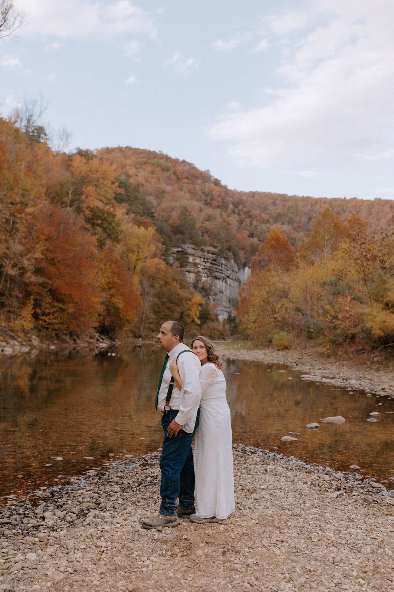 A couple embraces in front of a colorful fall at Steel Creek for their Buffalo National River elopement.