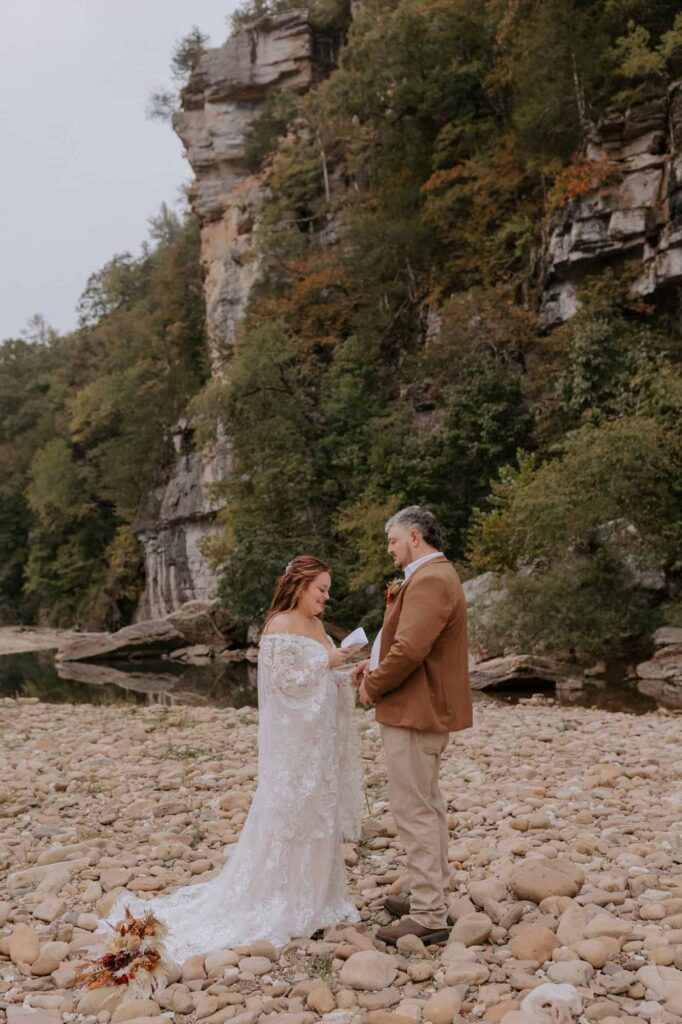 A bride reads her vows to her groom beside the Buffalo National River during their vow renewal at Steel Creek Campground in Arkansas.