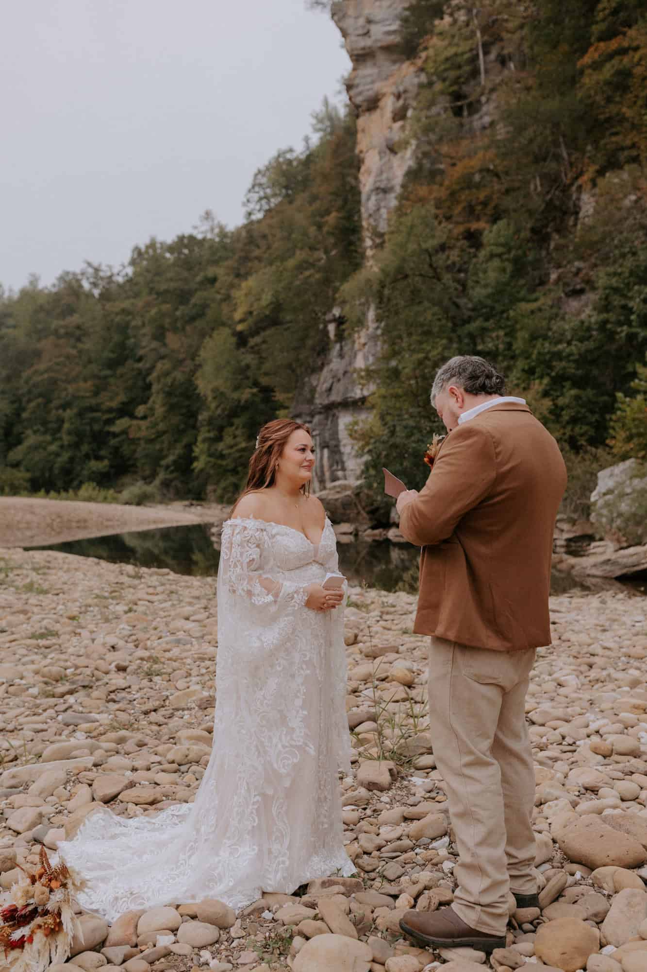 A groom and bride exchange vows next to the Buffalo National River during their Steel Creek elopement in Arkansas.