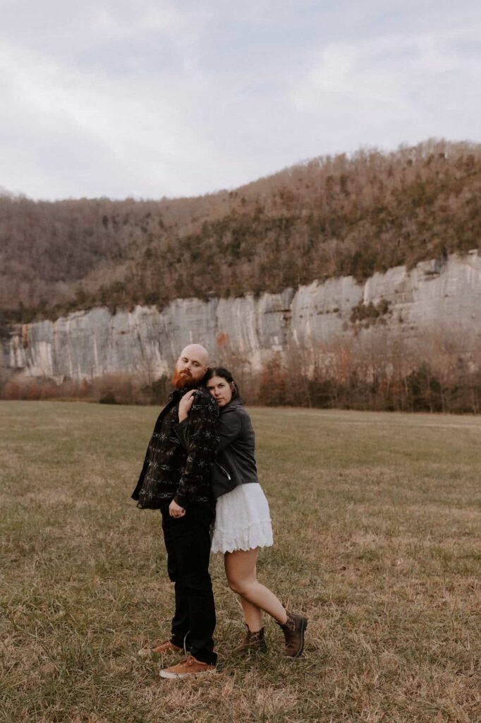 A couple poses for a photo in front of Roark Bluff at Steel Creek Campground during their Buffalo National River elopement.