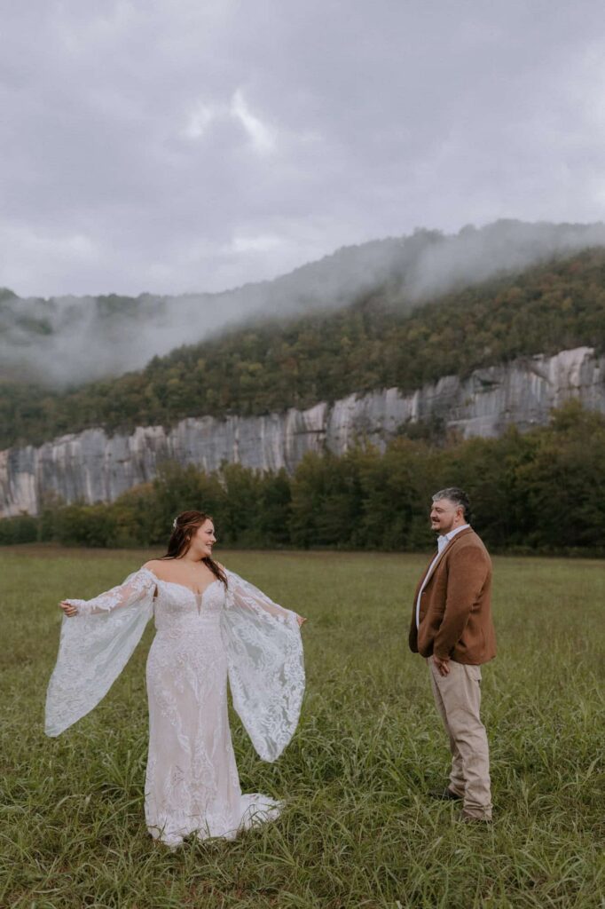 A bride shows off her dress to her groom during their elopement at Steel Creek Campground in front of the painted bluffs.