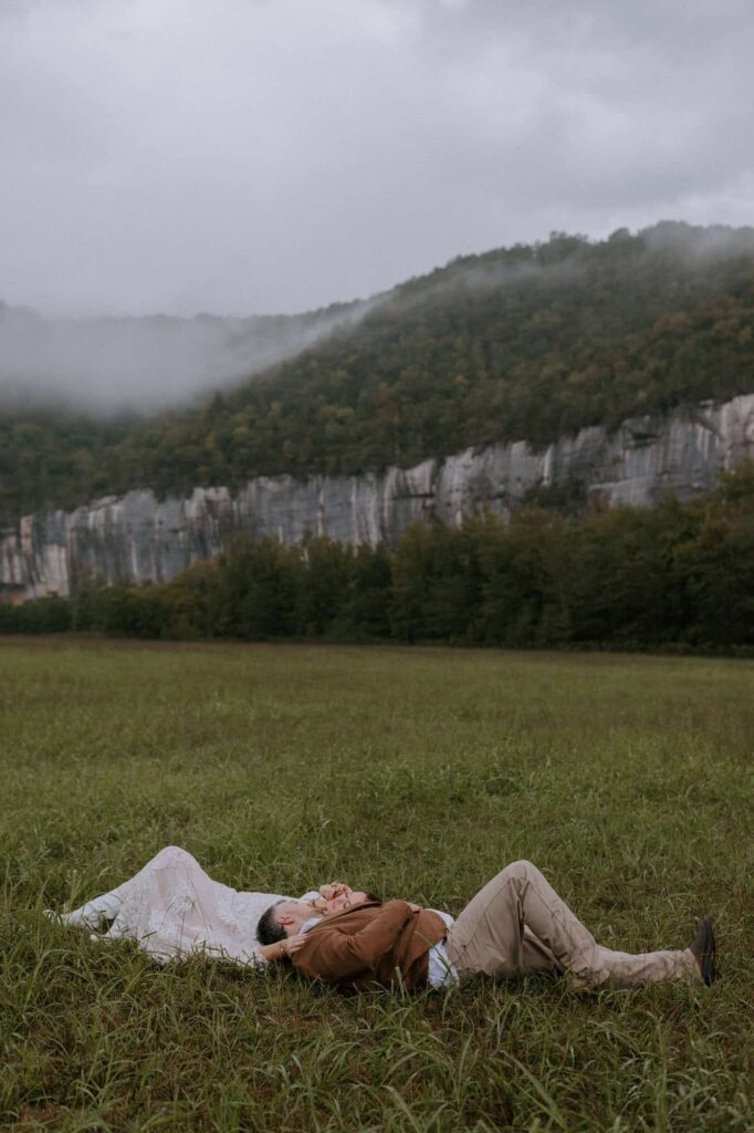 A couple lays in a grassy field overlooking painted bluffs at Steel Creek Campground.