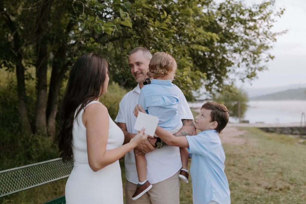 A wife surprises her husband with their original vow books on their 10th anniversary so that they can read them again during a vow renewal at Lake Leatherwood in Eureka Springs, Arkansas.