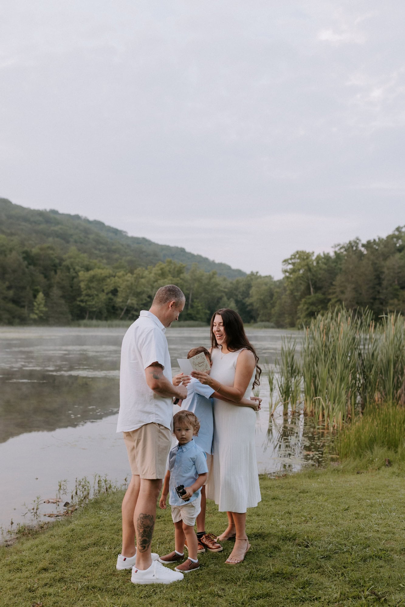 A wife reads her vows to her husband beside Lake Leatherwood in Eureka Springs, Arkansas during their sunrise vow renewal.