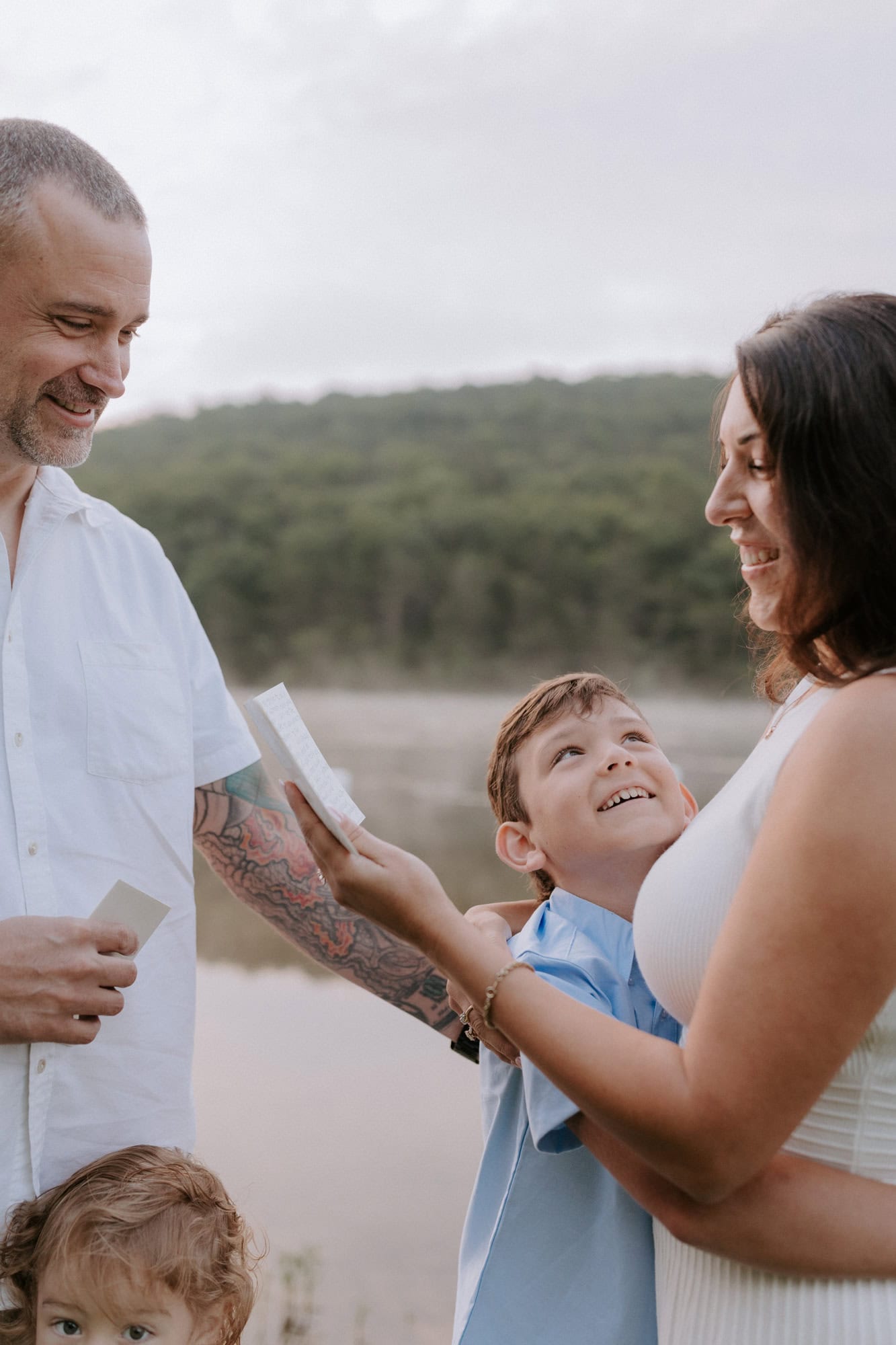 A child holds on to his mom while she reads her vows to her husband during their 10th anniversary vow renewal in Arkansas.